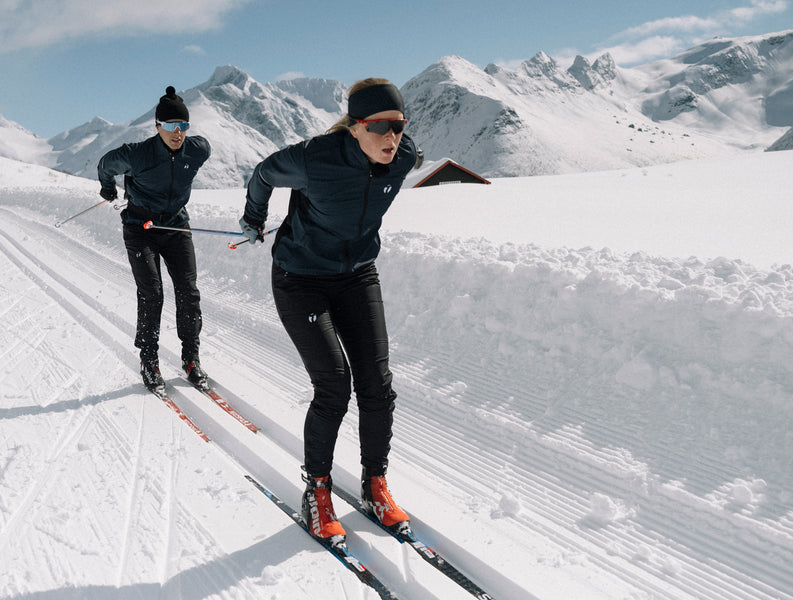 Two people skiing in full speed in their Ambition jacket and pants from trimtex