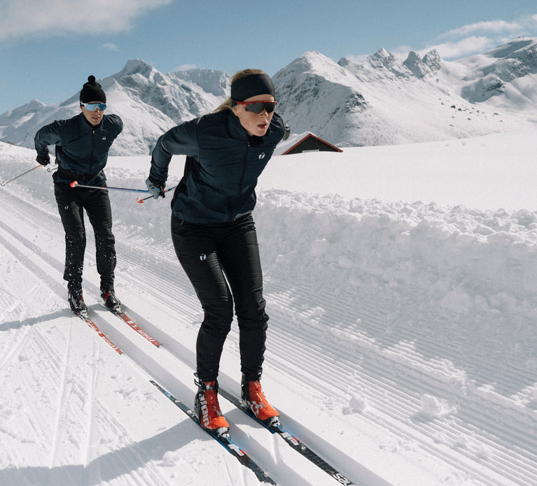 Two people skiing in full speed in their Ambition jacket and pants from trimtex