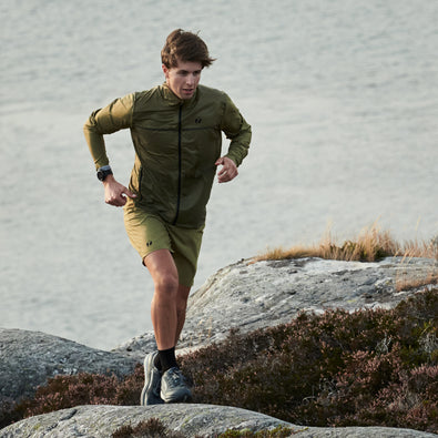 Man jogging up a hill wearing the Fast running jacket