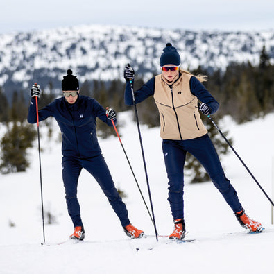 Man and woman skiing, wearing Trimtex Pulse Merino beanies and Ace skiing clothes.